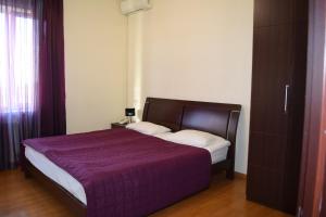 a bedroom with a bed with a purple comforter at Hotel Grig in Yerevan