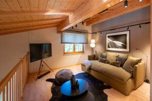 een woonkamer met een bank en een tv bij Chalet Gutsch Andermatt by HomeFlow in Arni Alp