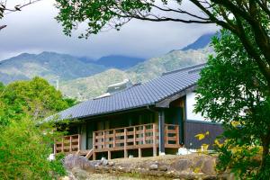 a house with a roof with mountains in the background at South Coast house in Yakushima
