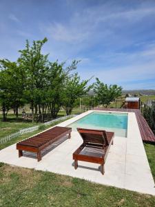 a swimming pool with two benches next to at Escondite Serrano in Villa Giardino
