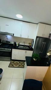 Una cocina con gabinetes blancos y un refrigerador negro. en green oasis vacation retreat, en La Grúa