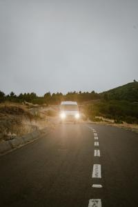 una furgoneta circulando por una carretera con las luces encendidas en Bawhee - Campervan, en Caniço 2 fotos más