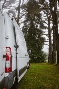 Dos furgonetas blancas estacionadas en un campo con árboles en Bawhee - Campervan, en Caniço