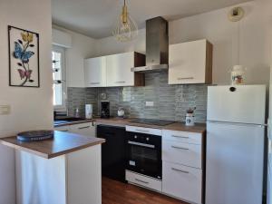 a kitchen with white cabinets and a white refrigerator at Couleur océan in Saint-Paul-lès-Dax