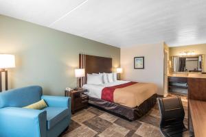 a hotel room with a bed and a blue chair at Econo Lodge Oak Grove-Blue Springs in Oak Grove