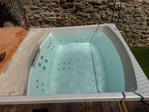 a jacuzzi bathtub in a backyard with a stone wall at Torre Medieval de Queralt & Spa in Concabella