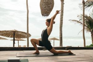 a woman doing a yoga pose in front of the beach at Chiringuito Tulum in Tulum