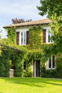 an ivy covered house with a lawn at PODERI LA ROCCHETTA Countryside Estate on the Hills of Lake Garda in San Felice del Benaco