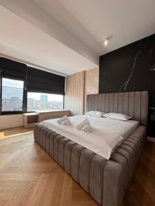 a large bed in a large room with a large window at Sky View Penthouse in Craiova