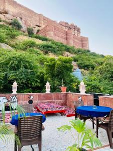 ジョードプルにあるMystic View Jodhpurの山の前にテーブルと椅子が備わるパティオ