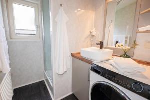 a bathroom with a sink and a washing machine at Ferienhaus Mellumplate 08 in Dorum Neufeld +22 photos
