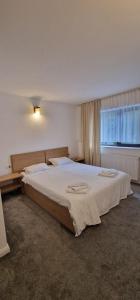 une chambre avec un grand lit blanc avec une fenêtre dans l'établissement Cheile Braitei, à Lupeni
