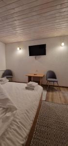 Cette chambre comprend 2 lits, une table et une télévision. dans l'établissement Cheile Braitei, à Lupeni 1 autre photo