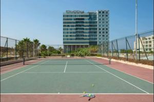 a tennis court in front of a tall building at Okeanos Sea Loft in Herzliya B +4 photos