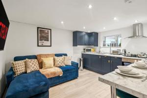 Una sala de estar con un sofá azul y una cocina. en Sleek and Stylish Yorkshire Gem - Sleeps 4, en Castleford