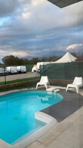 a pool with two white chairs and a tent at Résidence Foch in Trois-Moulins