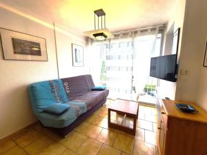 un salon avec un canapé bleu et une télévision dans l'établissement Appartement agréable avec piscine à Le Grau-du-Roi, au Grau-du-Roi