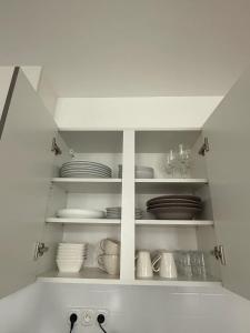 a kitchen with white plates and dishes on shelves at Bright apartment in the heart of Chimay, 40 m² with view in Chimay
