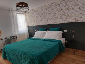 a bedroom with a green bed with a brick wall at Sepa in Chioggia +12 photos
