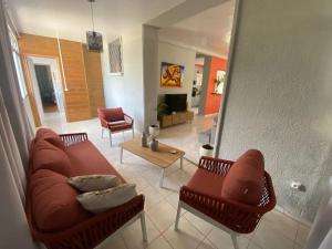 un salon avec un canapé et deux chaises dans l'établissement Appartement spacieux à Schoelcher avec piscine partagée, à Schœlcher