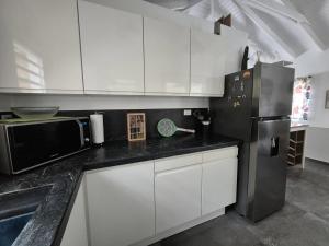 a kitchen with white cabinets and a black refrigerator at Cozy House with Terrace in Upper Prince's Quarter in Upper Prince's Quarter
