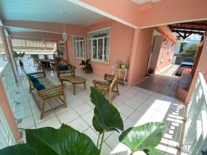 un porche ouvert avec des chaises et une table dans l'établissement Appartement spacieux à Schoelcher avec piscine partagée, à Schœlcher