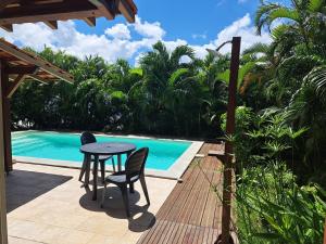 a table and chairs on a deck next to a pool at Studio Kerbignon, Piscine privée in Case-Pilote