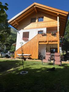 a house with a deck and chairs in the yard at Ciasa La Cate in Bellamonte