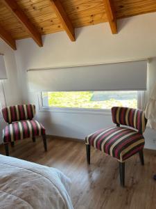 a bedroom with two chairs and a bed and a window at Cabaña Macar in Caviahue