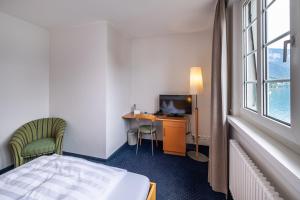a hotel room with a bed and a desk and a television at Parkhotel Gunten – Beach & Spa in Gunten
