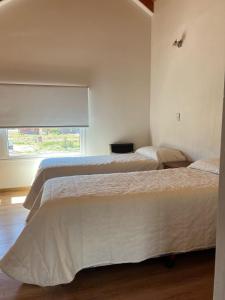 two beds in a bedroom with a window at Cabaña Macar in Caviahue