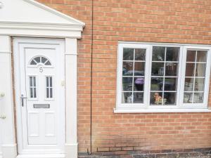 Ein Backsteingebäude mit einer weißen Tür und einem Hund im Fenster in der Unterkunft 5 Links Court in Skegness