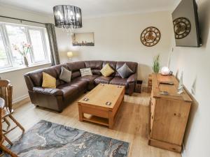 ein Wohnzimmer mit einem Ledersofa und einem Couchtisch in der Unterkunft 5 Links Court in Skegness
