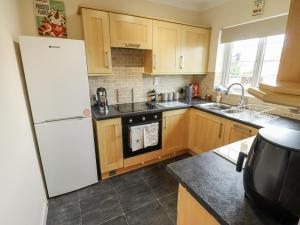 eine Küche mit Holzschränken und einem weißen Kühlschrank in der Unterkunft 5 Links Court in Skegness