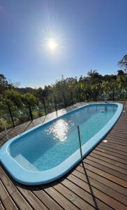 a large blue swimming pool on a wooden deck at Couples' Retreat with Pool and Hot Tub in Imaruí