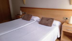 two beds in a hotel room with white sheets at Hostal Cabrerès in Cantonigros