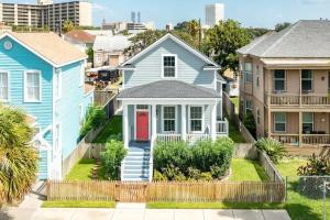 a blue house with a red door in a city at Exudes the Posh Life Heated Pool Fireplace & Stunning in Galveston