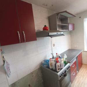 a kitchen with red cabinets and a counter top at Cozy room with balcony in Visaginas in Visaginas
