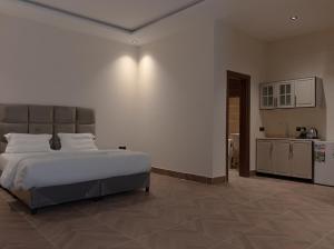 Un dormitorio con una cama grande y una cocina. en رايز العارض للشقق المخدومة, en Riad