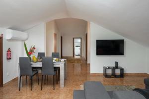 a living room with a table with chairs and a tv at OurMadeira - Ponta do Sol SeaView in Relógio do Poiso