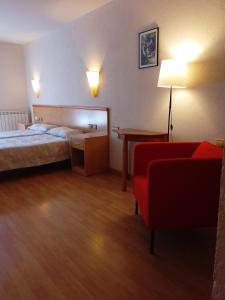 a hotel room with a bed and a red chair at Hostal Cabrerès in Cantonigros