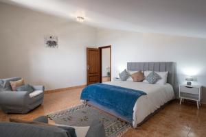 a bedroom with a bed and a couch and a chair at OurMadeira - Ponta do Sol SeaView in Relógio do Poiso