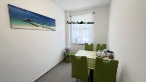 a dining room with a table and green chairs at Kim Homestay A Zimmer A2 in Sömmerda