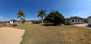 a yard with a playground and a house and palm trees at Sítio Cachoeira de Minas in Cachoeira de Minas