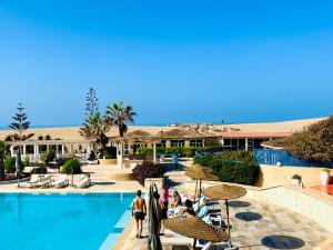 a group of people standing around a swimming pool at Ocean Dunes House in Mirleft