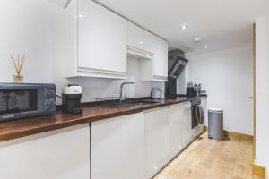 a kitchen with white cabinets and a microwave at Elegant 1BDR Flat with Private Patio in Twickenham