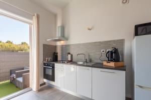 a kitchen with white cabinets and a sink and a window at Maison Coquillage in Saint-Mitre-les-Remparts +15 photos