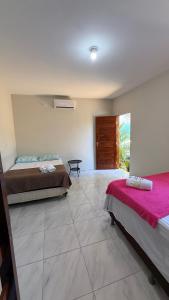 a large room with two beds and a window at Pousada Linhares in Canoa Quebrada