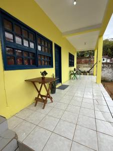 un patio con una mesa de madera y una pared amarilla en Casa para temporada Emygdio, en Santa Cruz Cabrália