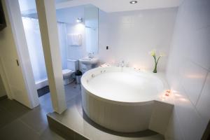 uma casa de banho branca com uma grande banheira e um WC. em Mariategui Hotel & Suites em Lima